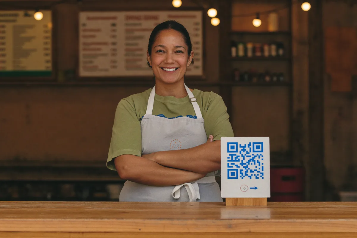 Dueña de un negocio con su cartel QR de facturación en el mostrador